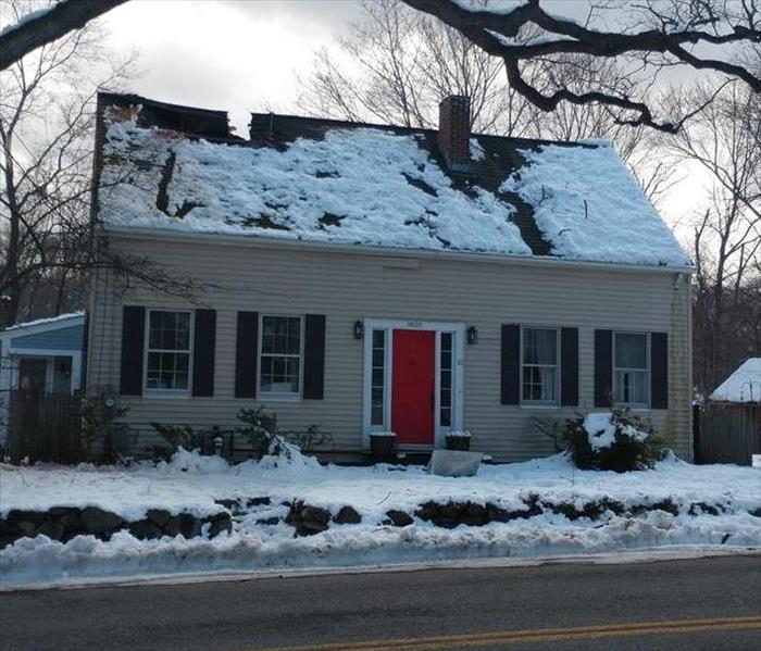 Cape style home covered in snow with badly damaged roof